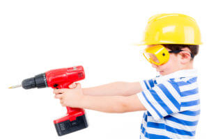 child with construction helmet and cordless screwdriver